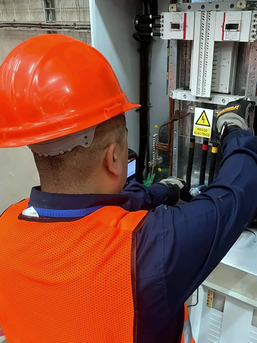 Conexión de pinzas amperimétricas sobre las barras de un tablero señalizado con riesgo eléctrico