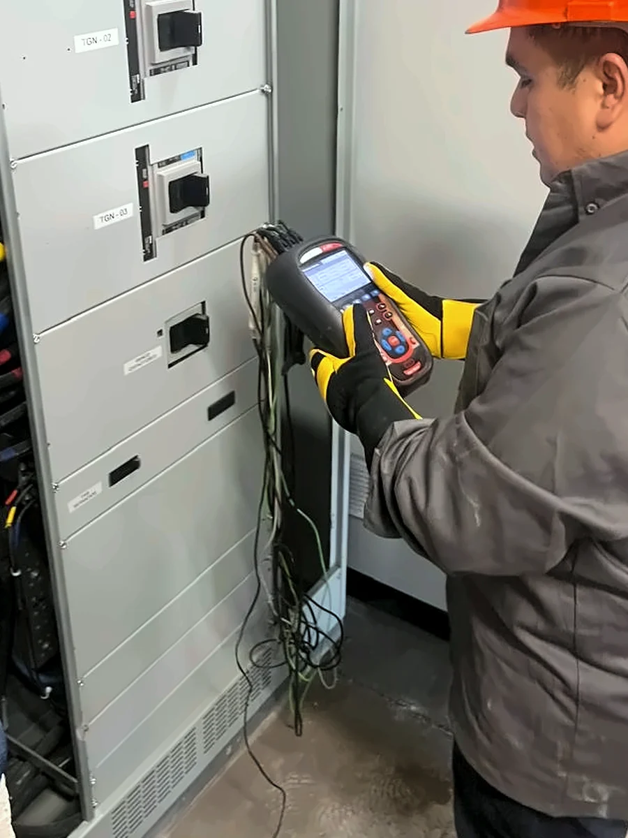 Técnico de ECONOVA con guantes dieléctricos registrando parámetros eléctricos con un analizador en un tablero de distribución